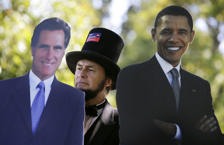 Abraham Lincoln impersonator Larry Elliott, of Louisville, Ky., stands next to cutouts of Republican presidential candidate Mitt Romney, left, and President Barack Obama outside the Norton Center on the Centre College campus before the vice presidential debate in Danville, Ky., Oct. 11.