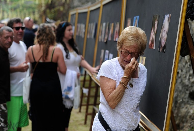 Emotional family members pay their respects at picture boards of the victims during the memorial service.