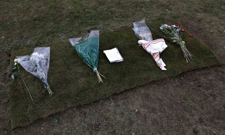Floral tributes and a piece of turf mark the spot where the headstone was removed from Jimmy Savile's grave.