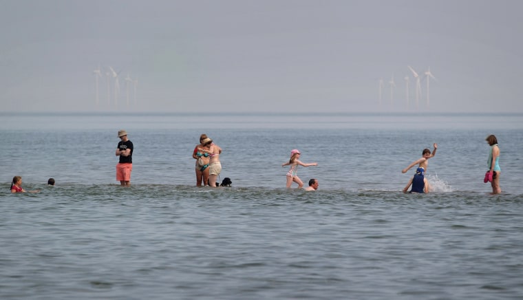 People enjoy a walk in the sea on a shingle bank known as The Street on Wednesday in Whitstable.