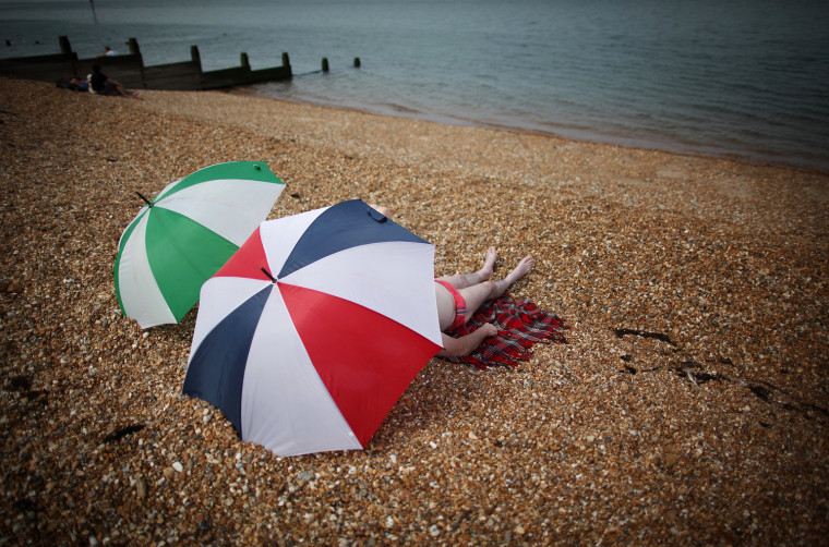 A couple rest under umbrellas on the beach on Wednesday in Whitstable, England.