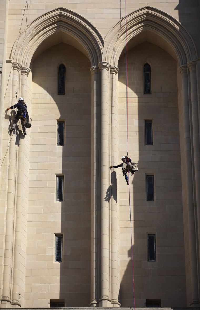 Katie Francis (L) and Emma Cardini, members of the Difficult Access Team from Wiss, Janney, Elstner Associates, use rapelling ropes to scale down one of the towers on the west front of the National Cathedral while looking for damage from August's magnitude 5.8 earthquake and high winds from Hurricane Irene October 17 in Washington, DC.