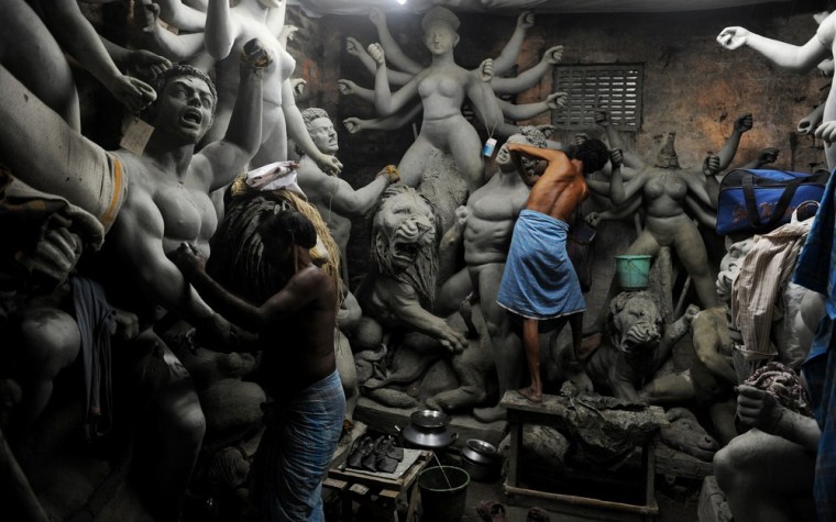 Artisans work on clay statues of the Hindu goddess Durga.