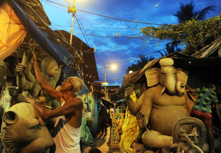 An artisan works on a statue of the Hindu goddess Durga.