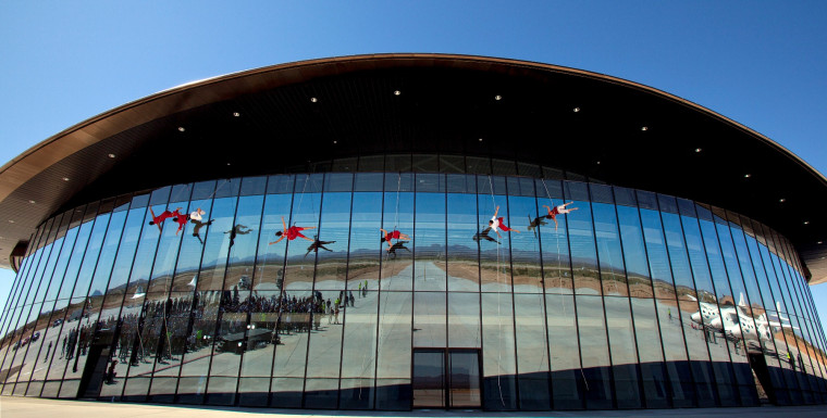 Dancers perform acrobatics on the glass facade of Spaceport America's terminal/hangar facility, which was christened as the Virgin Galactic Gateway to Space.