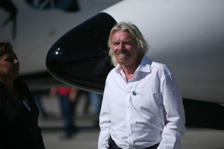 Virgin Galactic founder Richard Branson walks alongside the WhiteKnightTwo carrier airplane parked at Spaceport America in New Mexico.