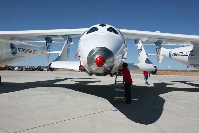 The SpaceShipOne rocket plane is nestled between the twin fuselages of its WhiteKnightTwo carrier airplane.