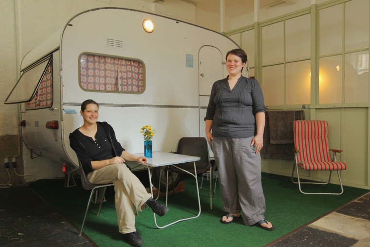 Silke Lorenz (L) and Sarah Vollmer pose next to one the campers they offer to guests as a hotel room at their Huettenpalast hotel on August 25, 2011 in Berlin, Germany.