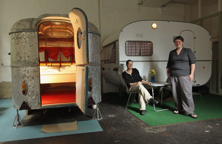 Silke Lorenz (L) and Sarah Vollmer pose next to two of the campers they offer to guests as hotel rooms at their Huettenpalast hotel on August 25, 2011 in Berlin, Germany.