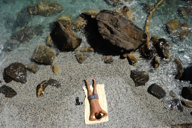 A vacationer sunbathes at a public beach near Santa Margherita Ligure, southern Genova, on Aug. 11.