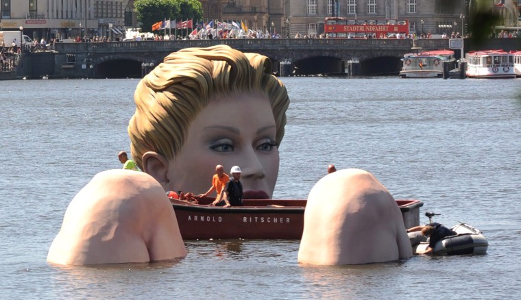 Workers fix the 'Giant Mermaid' at the inner Alster in Hamburg on Tuesday. The sculpture made by the artist and owner of an advertising agency Oliver Voss will stay in the inner Alster for the next ten days.
