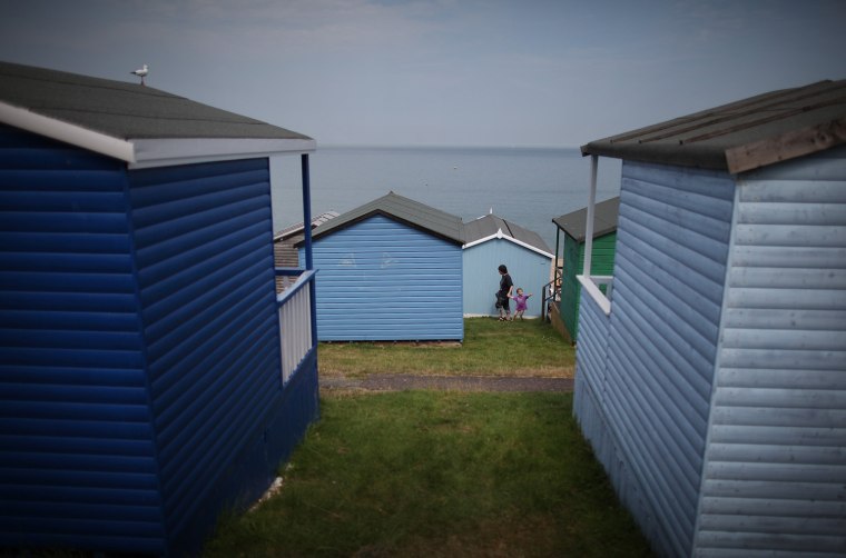 A mother and child walk between beach huts on Wednesday in Whitstable.