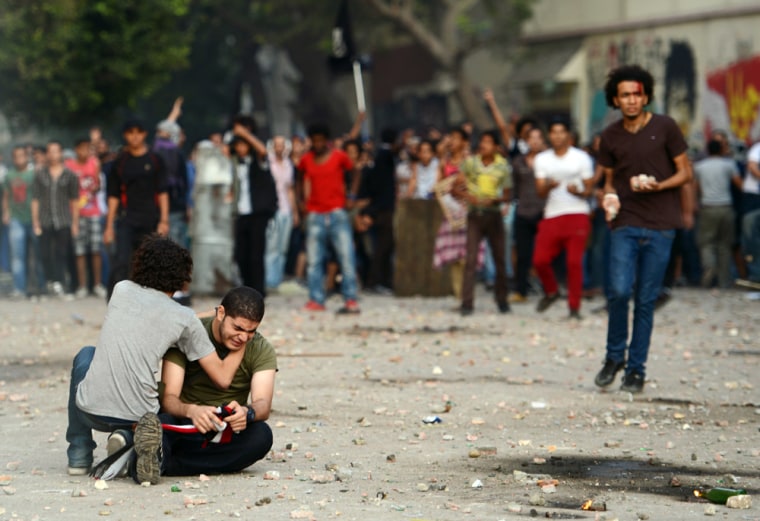 An anti-Muslim Brotherhood and President Mohammed Morsi protester cries on the ground as a man tries to calm him down during clashes with Morsi supporters in Tahrir square, in Cairo, Egypt, on Friday.