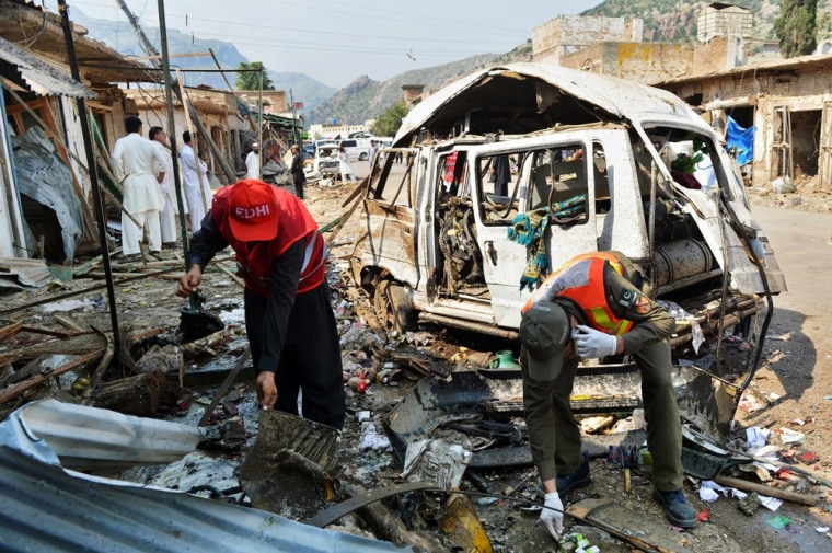 Pakistani security officials inspect the wreckage near a destroyed vehicle at the site of the attack.