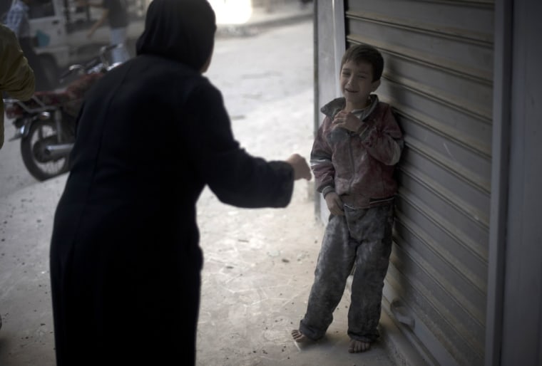 A frightened child stands in the street after a Syrian government artillery shell destroyed his family home in the Shaar neighborhood of the northern city of Aleppo on October 13, 2012.
