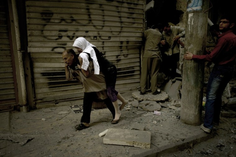 A man carries a woman from her destroyed home in the Shaar neighborhood of Aleppo on October 13, 2012.