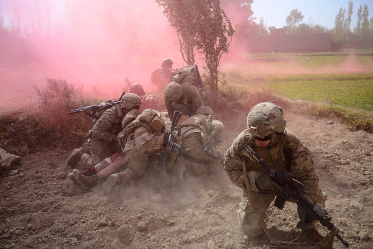 US Army soldiers attached to 2nd platoon, C troop, 1st Squadron (Airborne), 91st U.S Cavalry Regiment, 173rd Airborne Brigade Combat Team protect a wounded comrade, Private Ryan Thomas, from dust and smoke flares after an Improvised Explosive Device (IED) blast during a patrol near Baraki Barak base in Logar Province, Afghanistan on October 13, 2012.