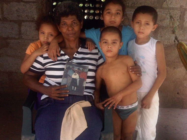 Sacorro Mendez-Flores, surrounded by her grandchildren, holds a family photo. The resident of Chichigalpa, Nicaragua, lost both her son and husband to chronic kidney disease.