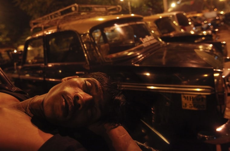 A taxi driver sleeps on the boot of his Premier Padmini at a taxi park in Mumbai on October 4, 2012.