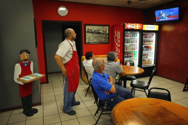 People watch the debate between President Barack Obama and Republican candidate Mitt Romney on television at Mamma Caruso's pizza restaurant in Miami, Florida on October 16, 2012.
