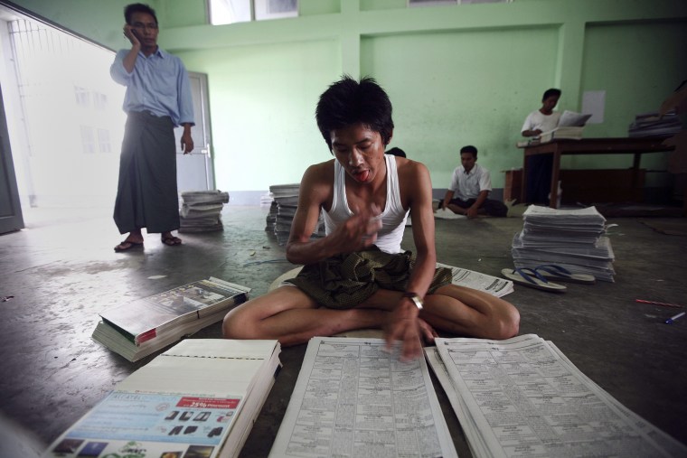 Employees manually insert advertising supplements into freshly printed copies of the New Light of Myanmar at the newspaper's office in Naypyitaw, Sept. 18.