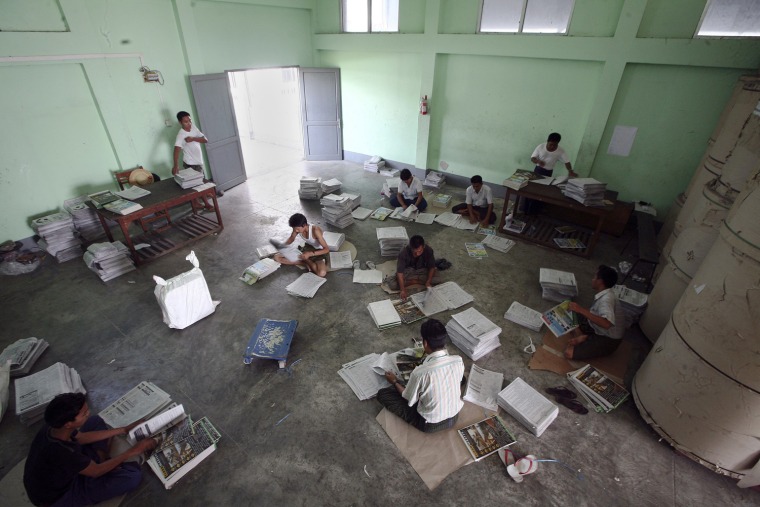 Employees manually insert advertising supplements into freshly printed copies of New Light of Myanmar at the newspaper's office in Naypyitaw, Sept, 18.