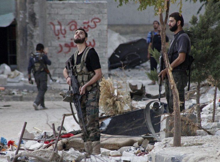 Free Syrian Army fighters hold their weapons as they look at a jet in the sky above Aleppo's Bustan al-Basha district on Wednesday.