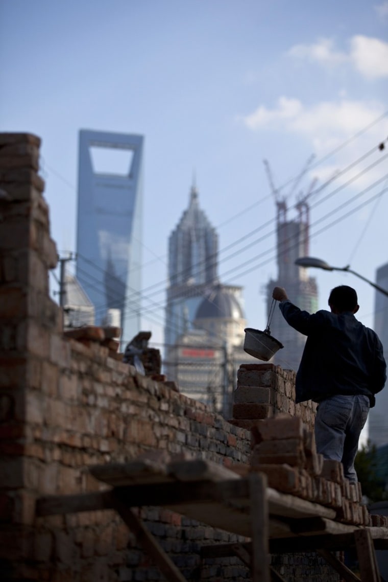 A worker holds a bucket as he builds walls at a construction site in central Shanghai on October 17, 2012.