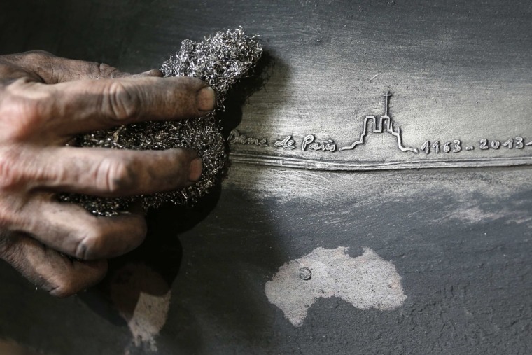 Craftsman Stephane Mouton cleans and inspects the bronze bell 'Maurice' after removing the mold at the French bell foundry Cornille Havard.