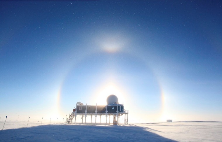 Buildings at Greenland's Summit Station are silhouetted by the sun and atmospheric effects.
