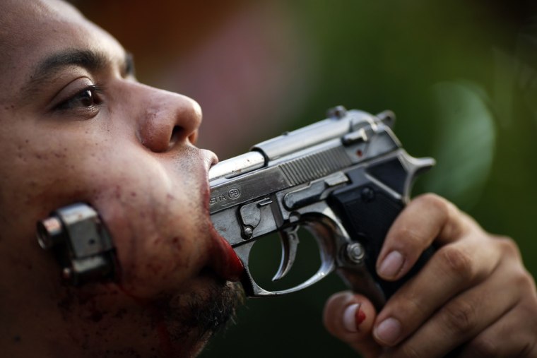 A devotee of Ban Tha Rua Chinese shrine with a gun pierced through his cheek takes part in a procession celebrating the annual vegetarian festival in Phuket on October 19, 2012.