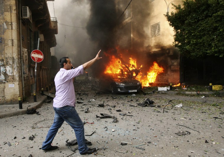 A man reacts near a burning car at the site of an explosion in Ashafriyeh, central Beirut, on Oct. 19. At least eight people were killed and 78 wounded by a bomb that exploded in central Beirut on Friday, the state news agency said.