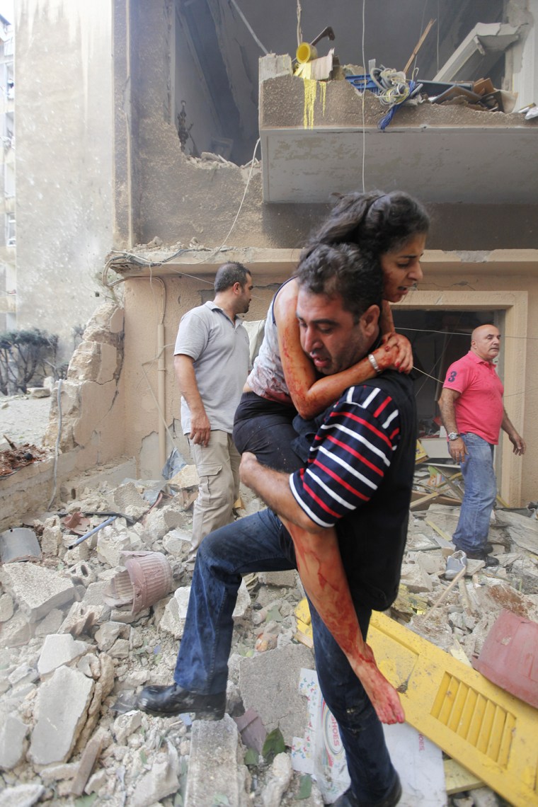A Lebanese civilian carries an injured woman at the scene of an explosion in the mostly Christian neighborhood of Achrafiyeh, Beirut, Lebanon, on Oct. 19.