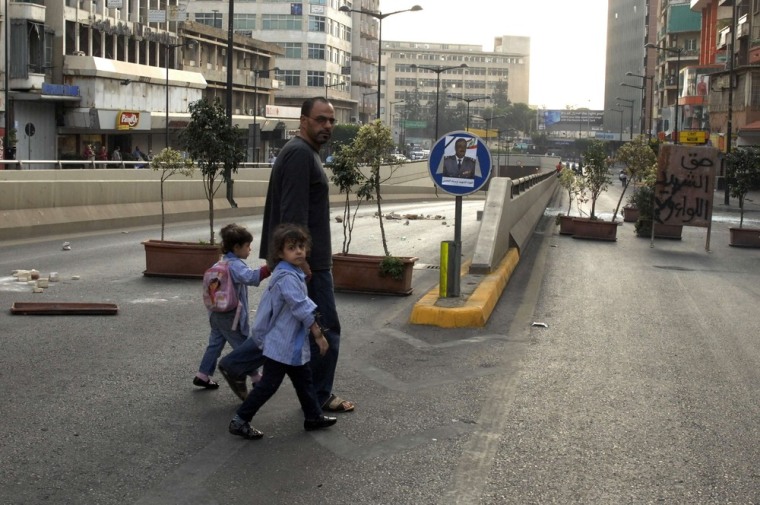 A man and his children walk away from clashes between Sunni Muslim gunmen and members of the Lebanese army in Kaskas, Beirut, October 22, 2012.