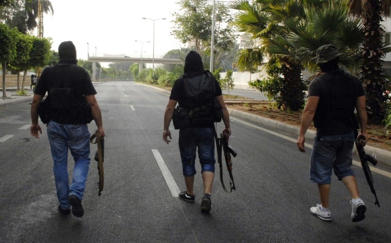 Sunni Muslim gunmen with weapons walk through the streets of Kaskas in Beirut on October 22, 2012, after a night of tension following the funeral of an intelligence official killed by a car bomb. Sunday's clashes fed into a growing political crisis in Lebanon linked to the civil war in neighboring Syria.