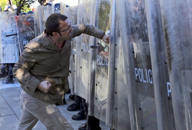 A supporter of opposition party Vetevendosje (Self-determination) hits at a police cordon during a protest in Pristina, Kosovo, on Oct. 22. Kosovo police fired teargas at the crowd attempting to storm the parliament in Pristina to protest against talks of Kosovo's Prime Minister Hashim Thaci with his Serbian counterpart Ivica Dacic last week in Brussels, Belgium. The protest was called by the Kosovo Albanian nationalist movement Vetevendosje (Self-determination), which fiercely opposes the EU-sponsored talks with Serbia aimed at improving relations. Serbia refuses to accept Kosovo's 2008 decleration of independence and Vetevendosje insists that Pristina should not negotiate with Belgrade as long as it continues to claim sovereignty over its breakaway province.