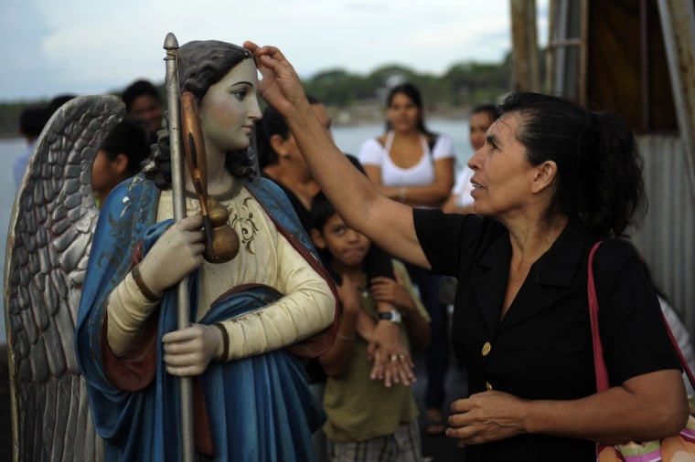 Believers touch the image of Saint Raphael the Archangel before the start of a procession, at the port of La Libertad on Oct. 23.