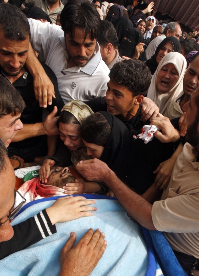 Palestinian mourners gather around the body of Hamas militant Loay Abu Jarad during his funeral in Beit Lahia, northern Gaza Strip, on Oct. 24. Militants from Gaza's ruling Hamas movement and other gunmen pummeled southern Israel with dozens of rockets and mortars early Wednesday and two Palestinians died of wounds sustained in Israeli airstrikes, in a sharp escalation of violence following a landmark visit to Gaza by the leader of Qatar.