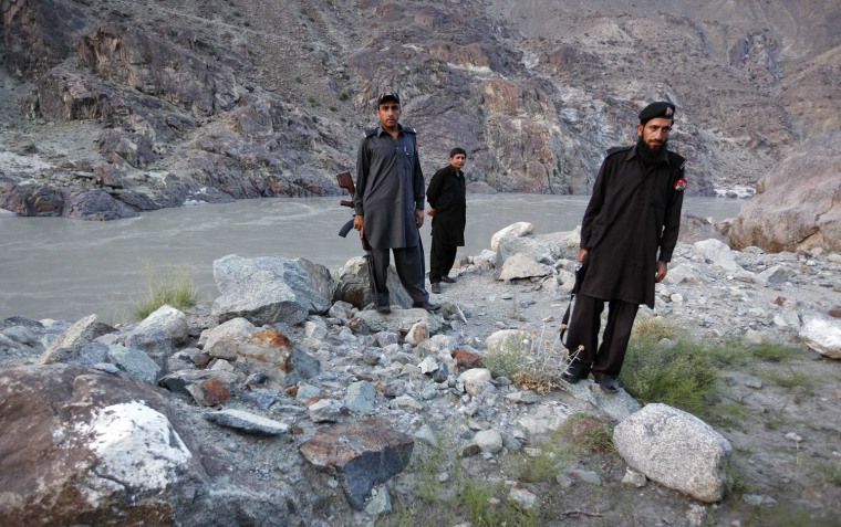 Police officers Jumma Gul, center, Khan Bahadur, right, and Gul Zaman, stand at the spot where bus passengers were gunned down in the Harban Nala area of Pakistan on Feb. 28.