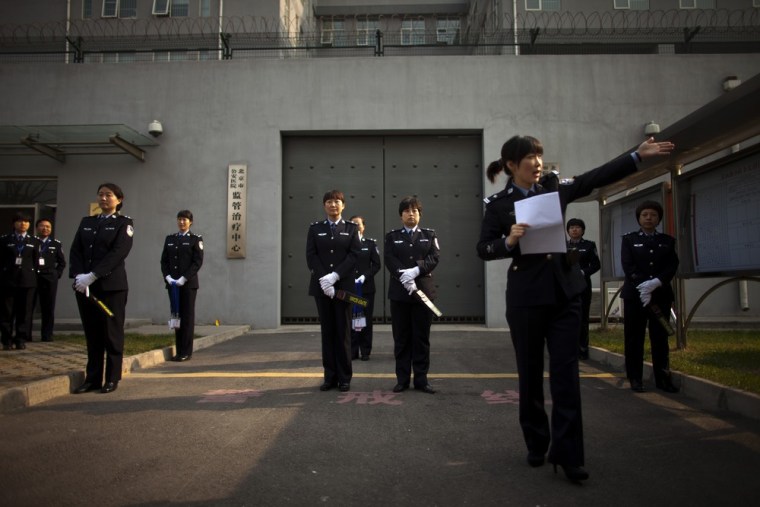 Police officers wait to perform a security check on visiting journalists outside the gate of the Number Two Detention Center.