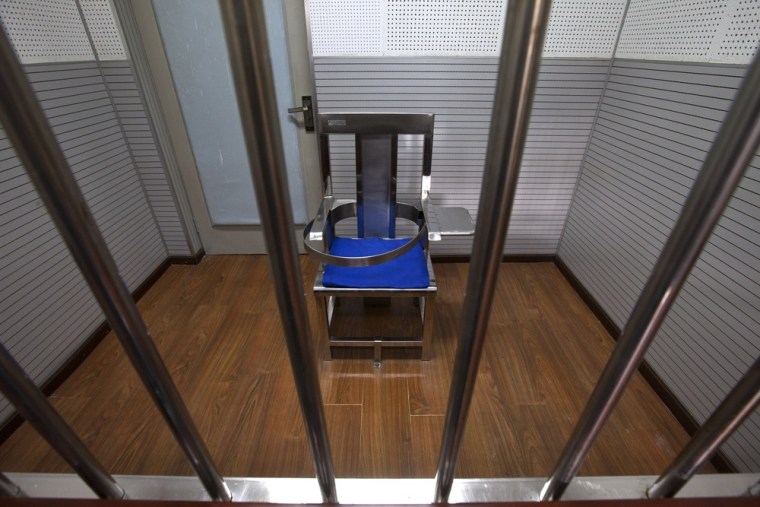 A chair specially designed to restrain the inmate is set behind bars in an interrogation room at the Number One Detention Center.