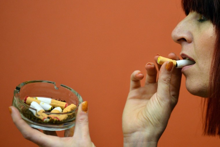 A woman eats an edible cigarette made from ginger bread at the 'Eat Your Heart Out 2012' cake shop in the Pathology Museum.