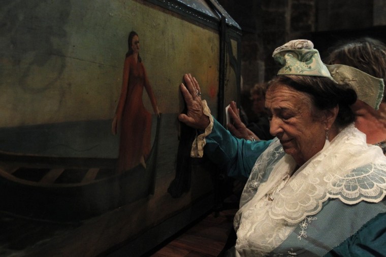 A gypsy woman touches a decorated display case containing the relics of Saint Mary Salome and Saint Mary Jacobe.