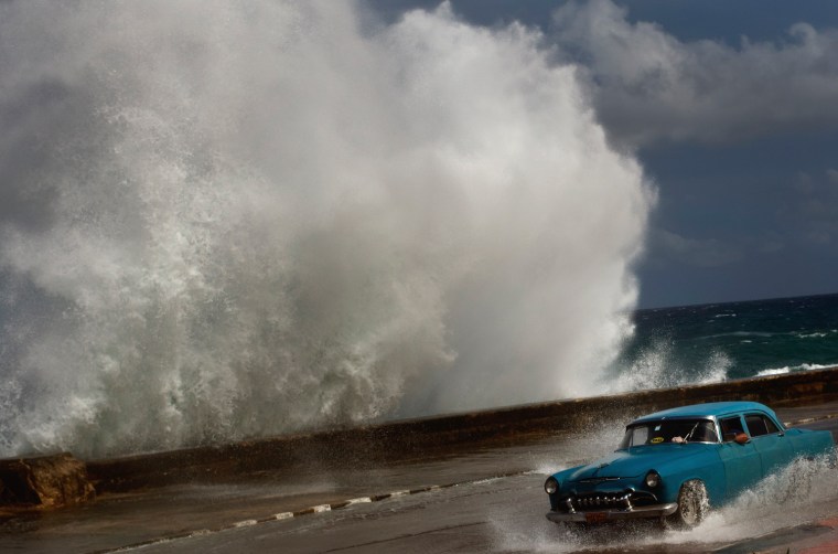 A driver maneuvers his classic American car along a wet road as a wave crashes against the Malecon in Havana, Cuba, on Oct. 25. Hurricane Sandy blasted across eastern Cuba on Thursday as a potent Category 2 storm and headed for the Bahamas after causing at least two deaths in the Caribbean.