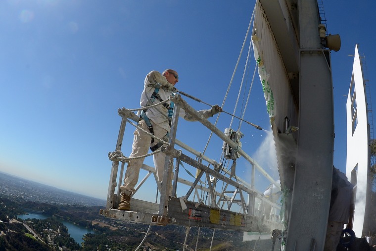 Workers use window-cleaner style platforms as they strip down the 50-foot (15-meter) tall letters, power washing the corrugated iron while restoring the Hollywood sign on Friday.