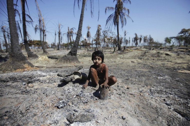 A girl joins others collecting pieces of metal from the rubble in a neighborhood in Pauktaw township that was burned in recent violence October 27, 2012.