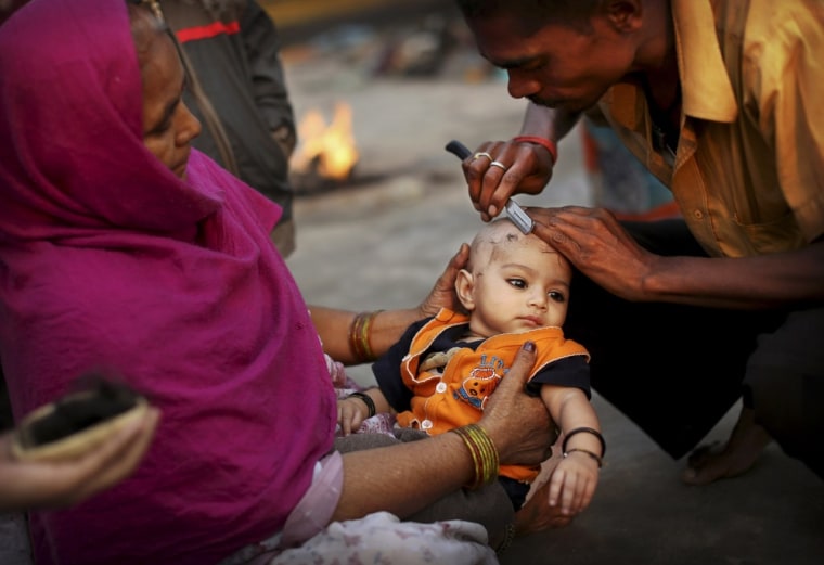 A barber gives a Hindu boy his first haircut before going for a holy dip in the Yamuna river on Sharad Purnima, an auspicious day for the new moon in the fall, in New Delhi, India on Oct. 29, 2012.