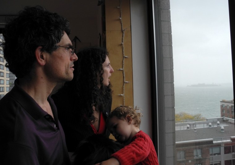 Claire Wladis, 34, holding her 21-month-old daughter Iliana, and her husband, Nicholas Rennie, 45, look across the Hudson River toward New Jersey early Monday, trying to assess how high the water had risen. The couple decided to stay in their lower Manhattan apartment despite Mayor Michael Bloomberg's mandatory evacuation order, saying they felt safer there than anywhere else.
