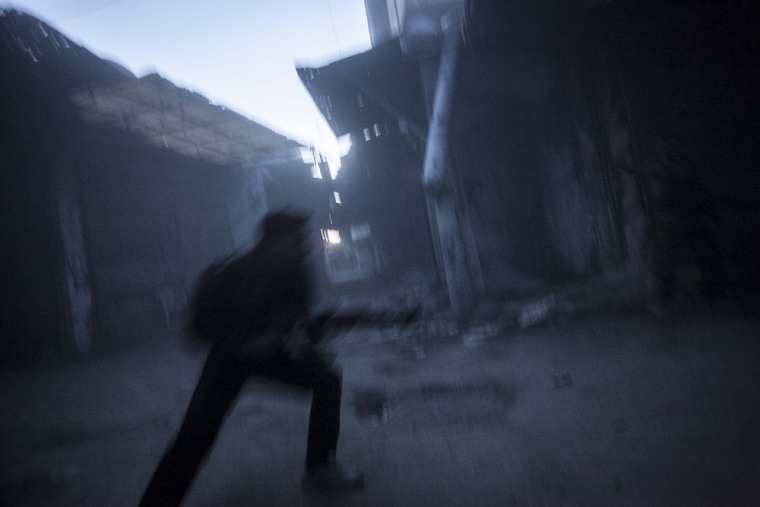 A rebel fighter belonging to the Qatebee Sokor Al-Islam group runs for cover as a Syrian army tank shells the rebel position during clashes in the Jedida district of Aleppo on Oct. 29, 2012.