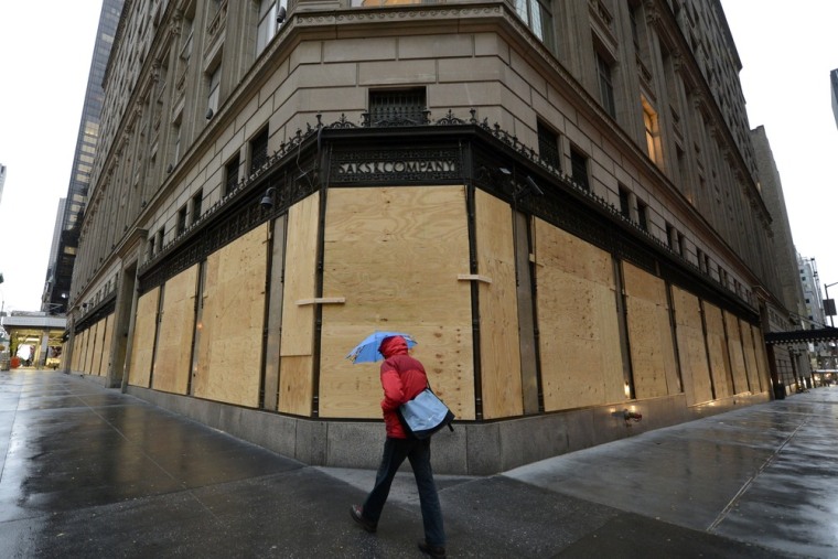 A woman walks past a boarded up Saks Fifth Avenue. Saks says it plans to reopen its flagship Manhattan store, seen boarded up here before superstorm Sandy struck, on Wednesday.